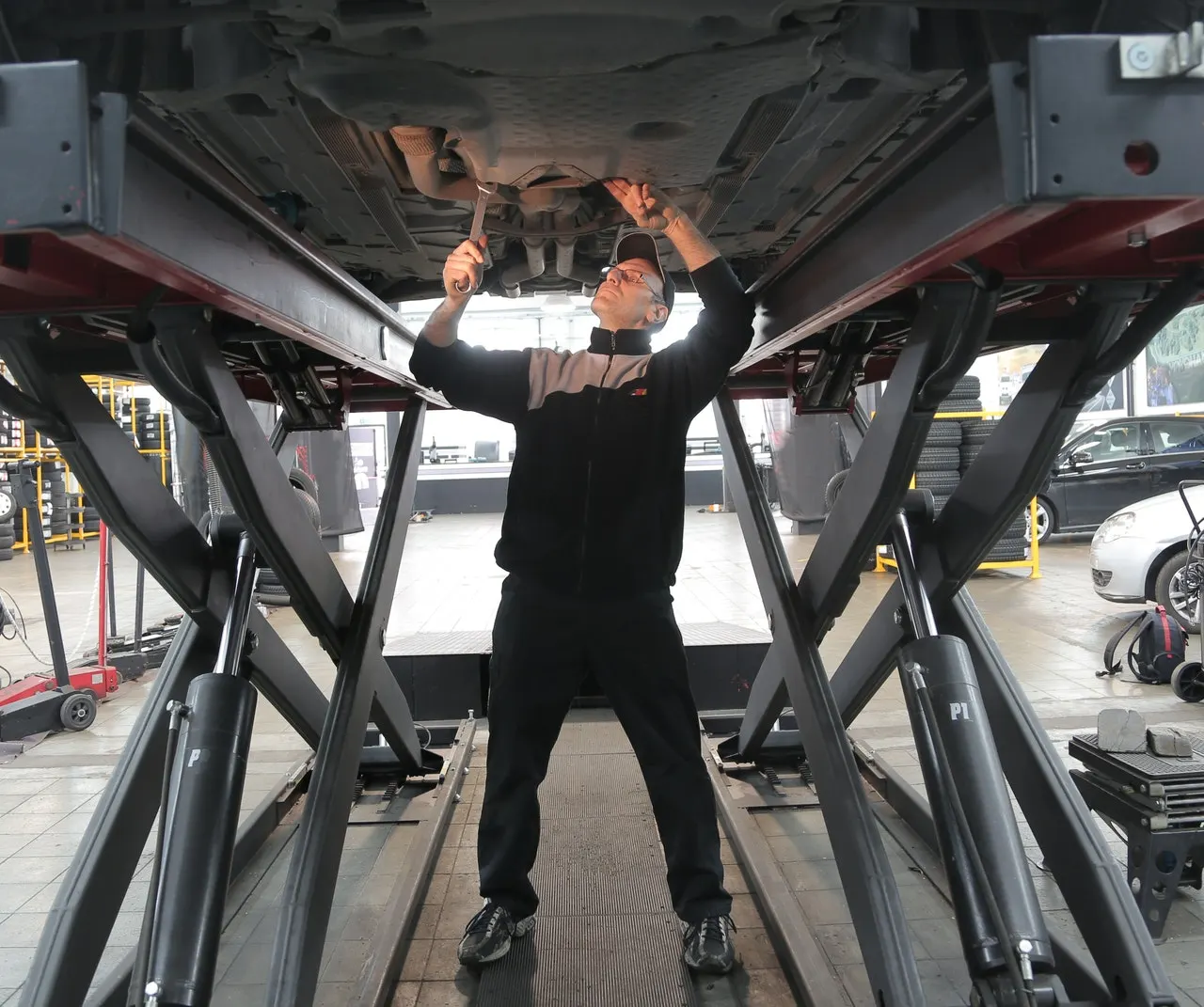 Mechanic works on under carriage of car